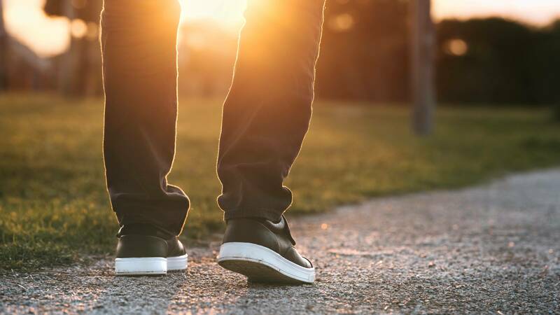 Feet walking on a path outdoors toward a hopeful, sunny future